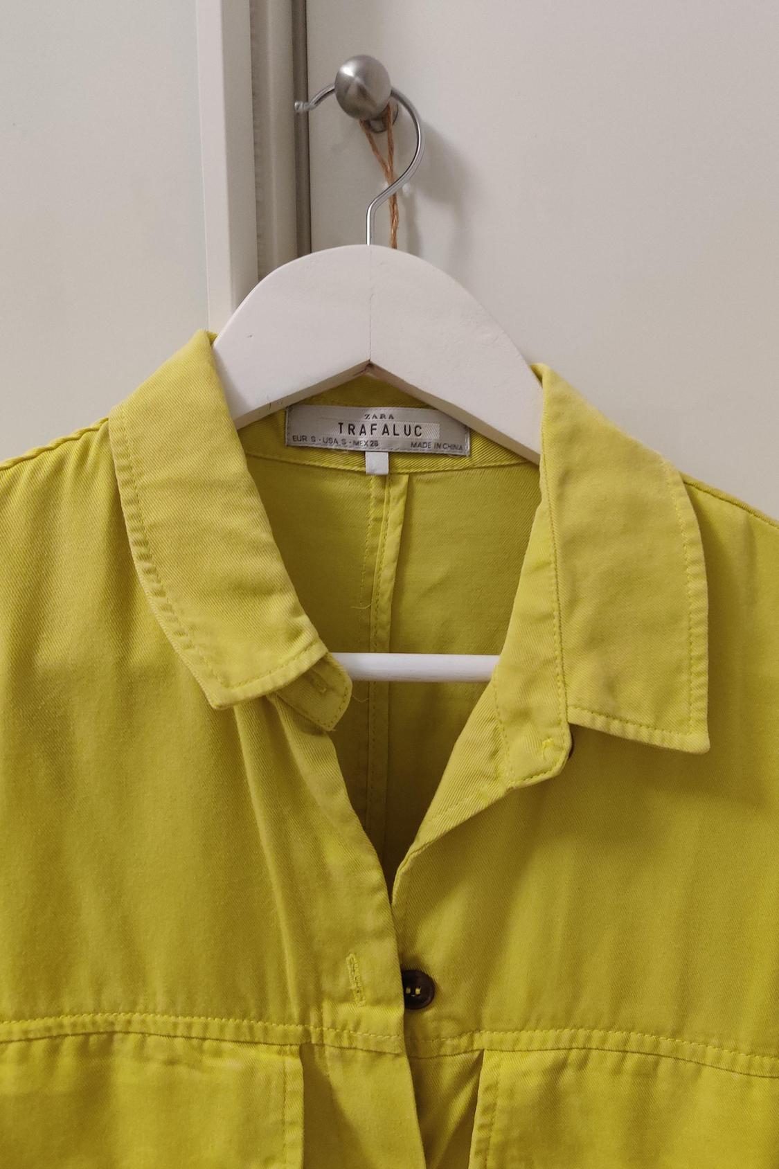 Collar and button placket detail of a yellow shirt with 'ZARA TRAFALUC' text on the label.