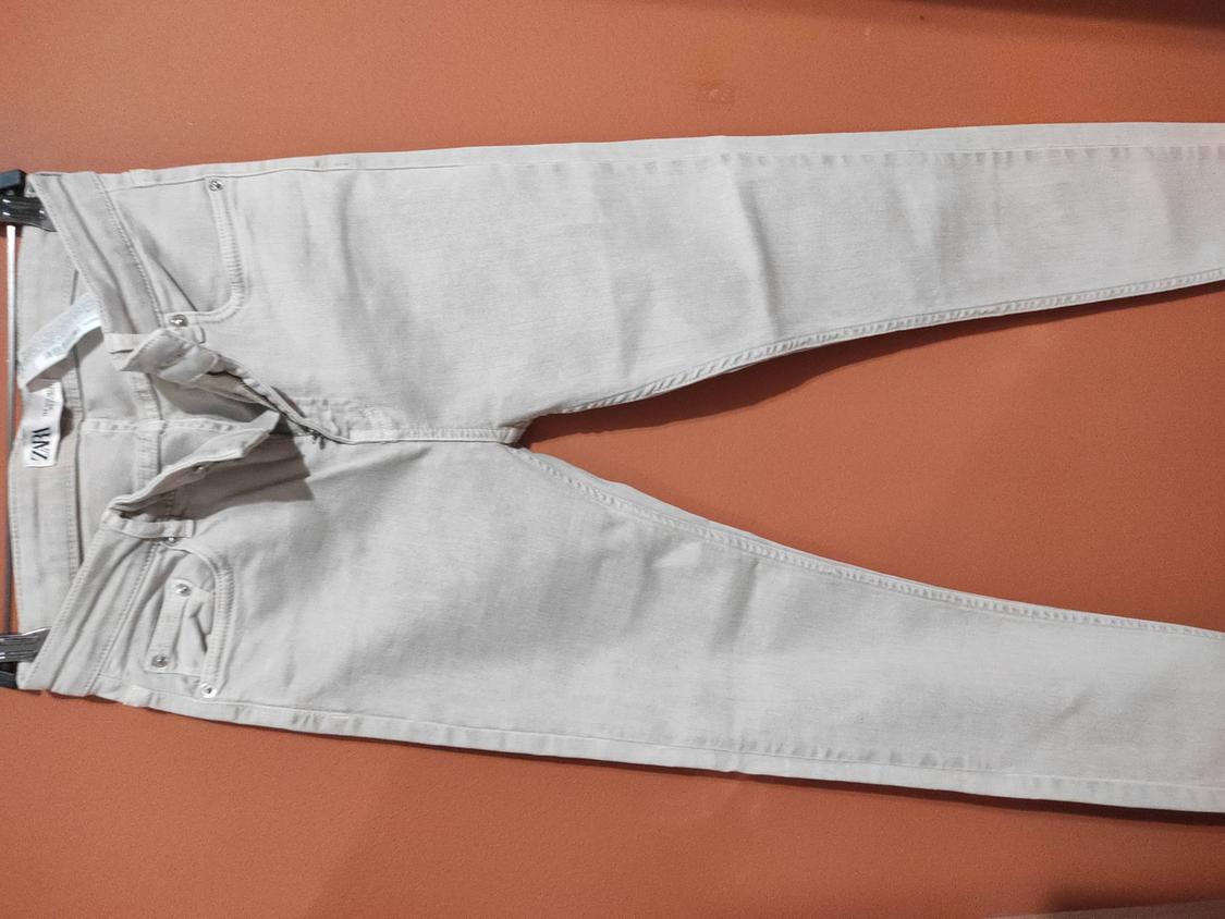 Light grey jeans laid flat on an orange background. Label visible on the waistband with the text "MZ".