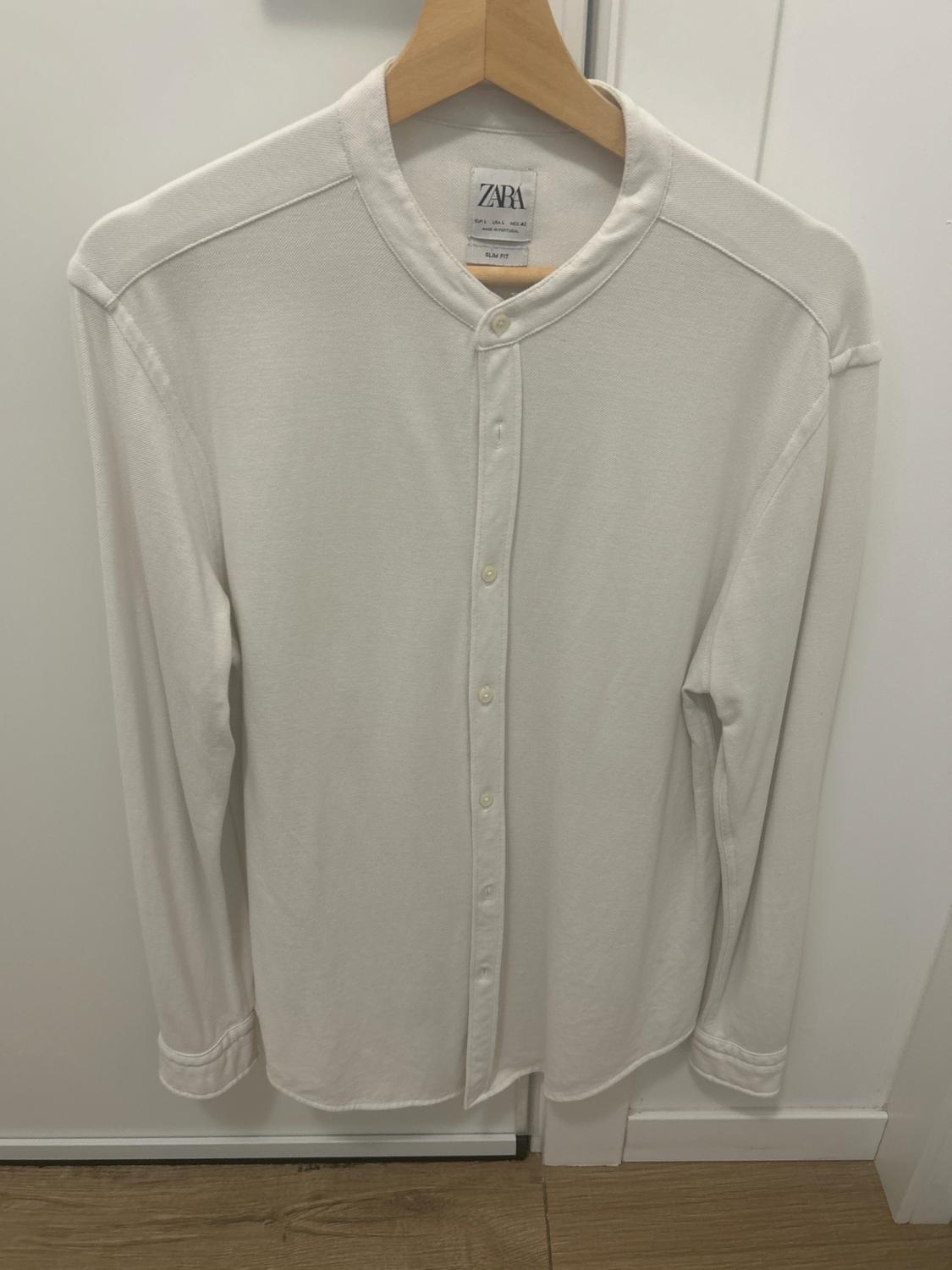 White long-sleeved shirt hanging on a wooden hanger, with a grandad collar and front buttons. Visible label: "ZARA SLIM FIT".
