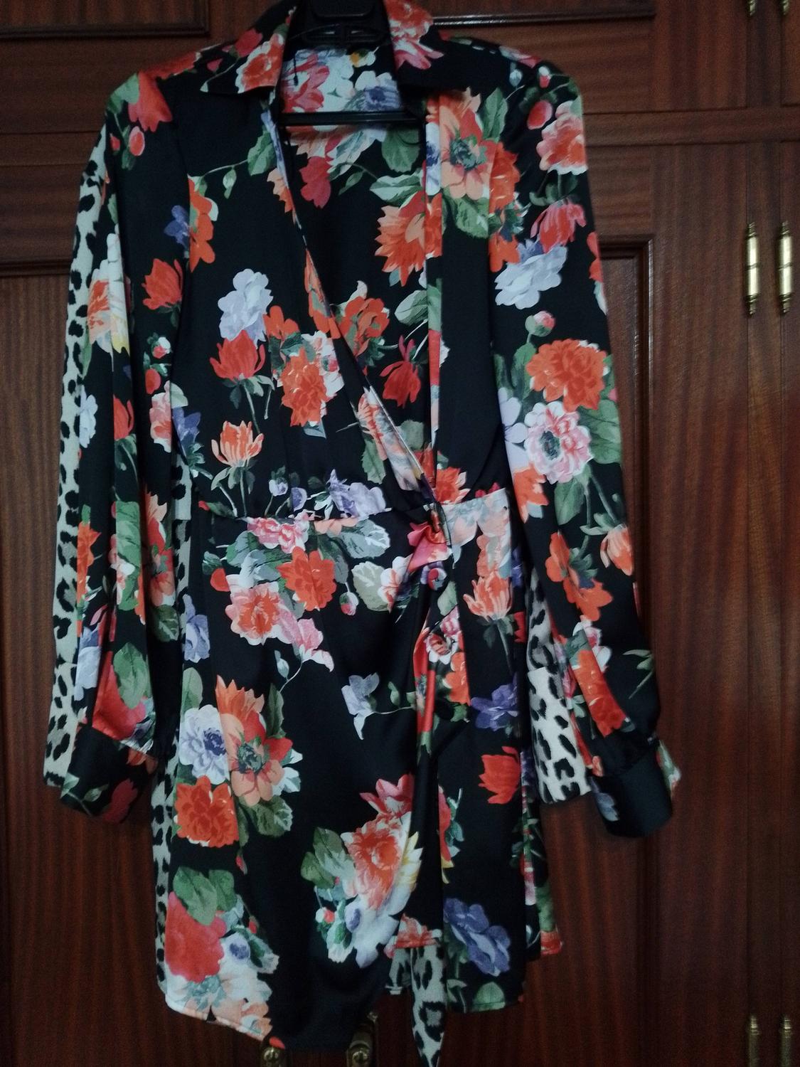 Dress with a floral print in red, white, and green tones on a black background, with animal print details on the sleeves.