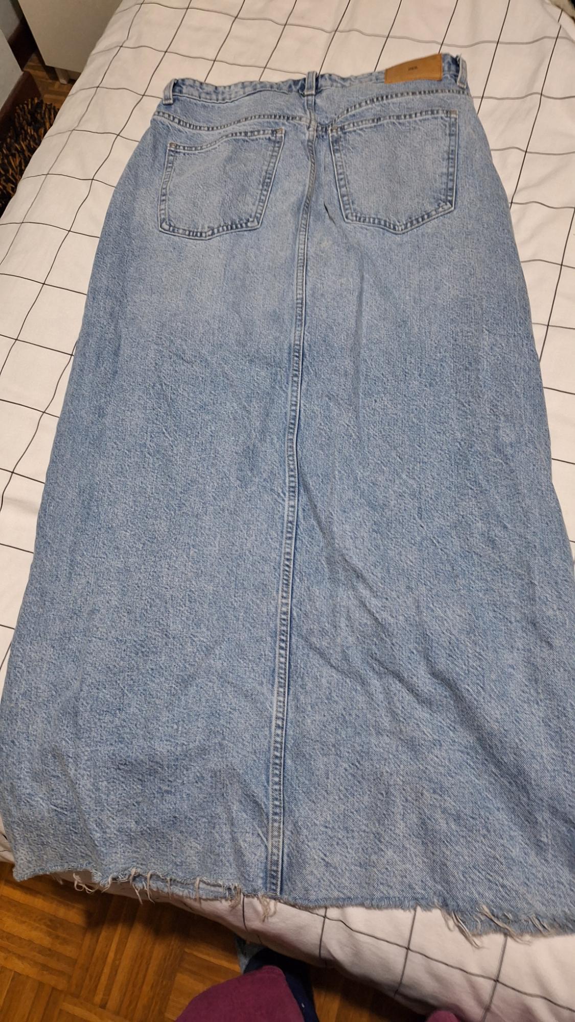 Light blue denim maxi skirt with back pockets, laid on a bed with a black and white checked bedspread.