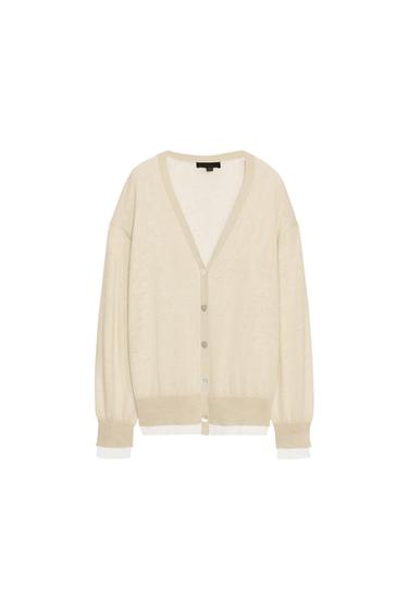 Front view of a knitted sand-coloured jacket with a V-neck, long sleeves and front button fastening. Double fabric detail.