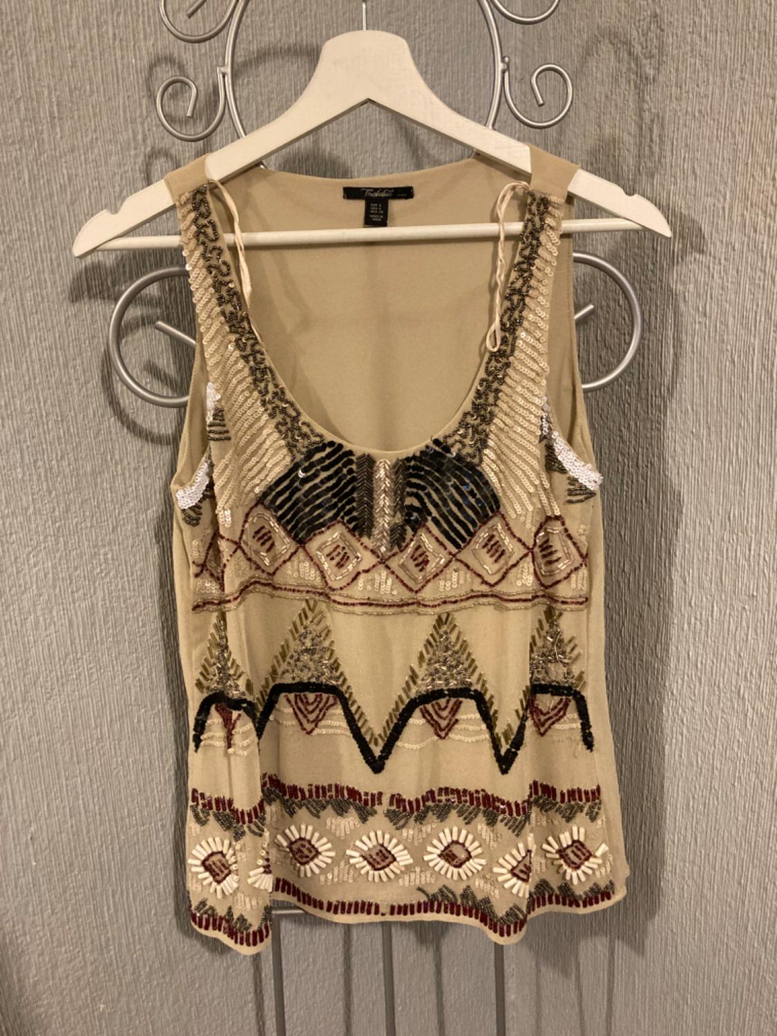 Front view of a beige blouse with geometric embroidery in brown and black tones.