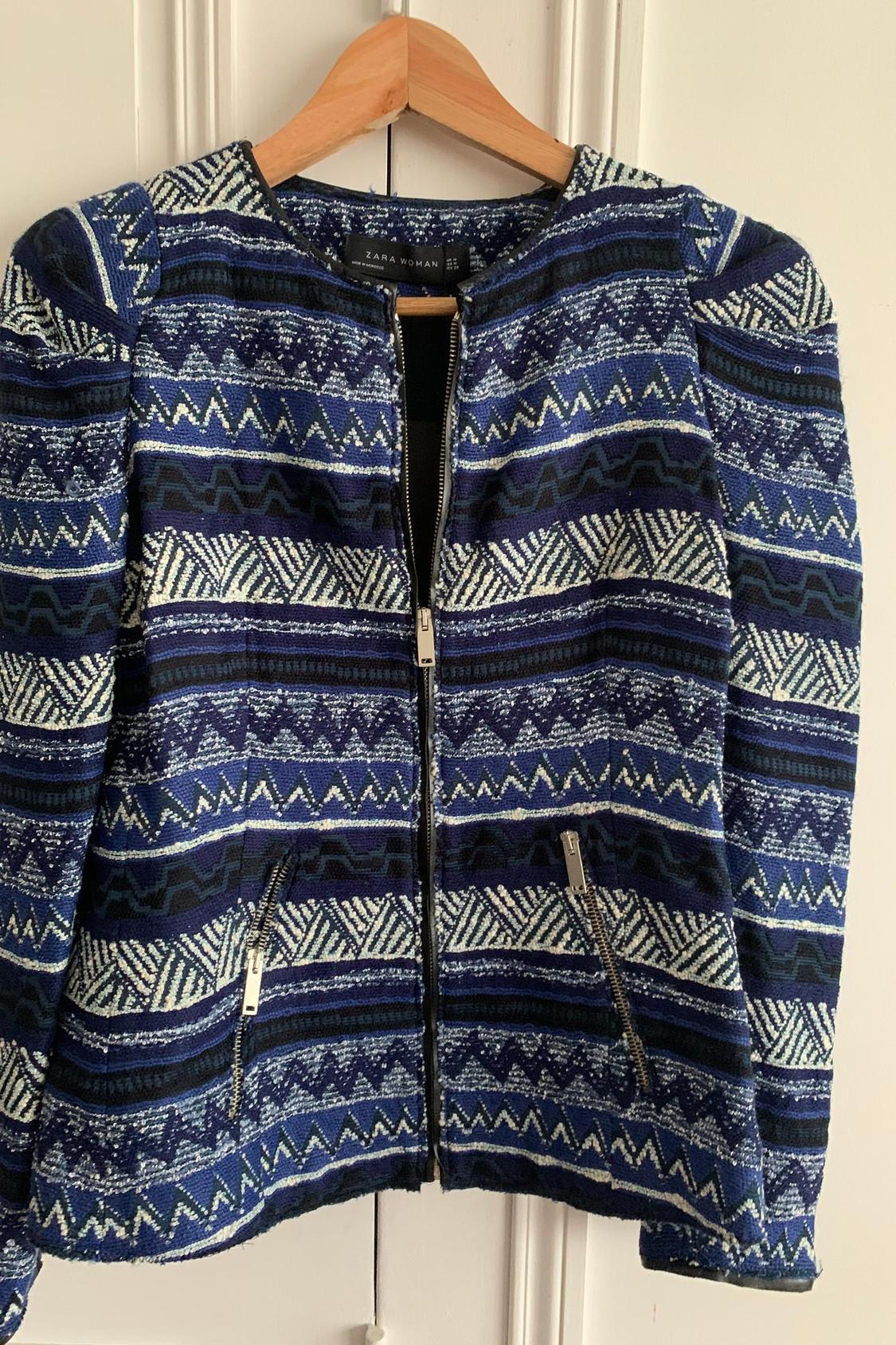 Front view of blue jacket with geometric print and front pockets with zips.