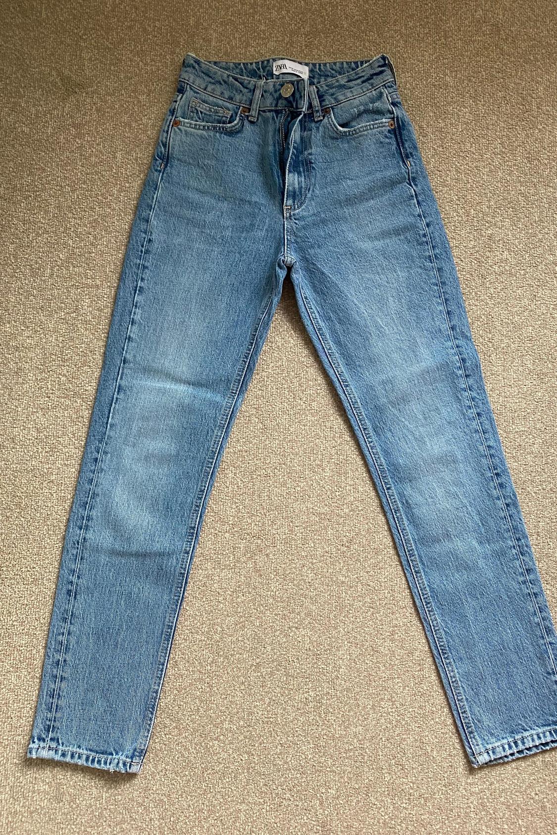 Front view of blue jeans with front pockets and visible button.
