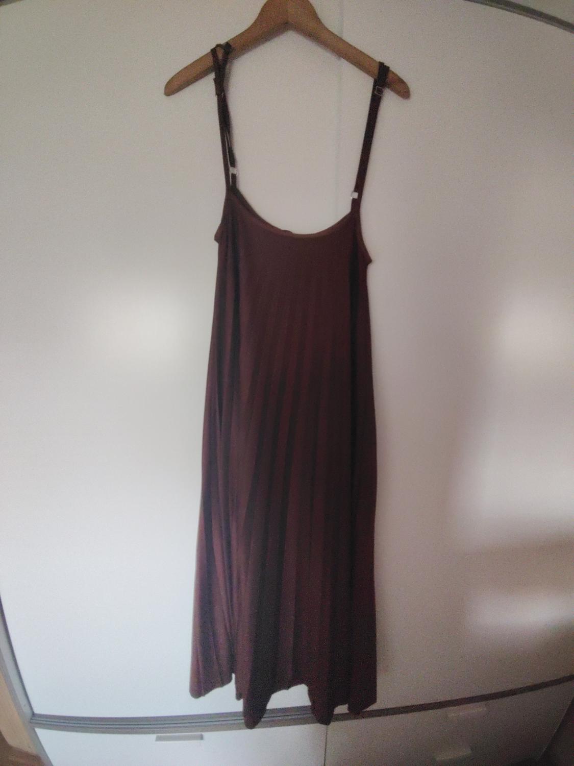 Brown long dress with thin straps hanging on a wooden hanger against a white background.
