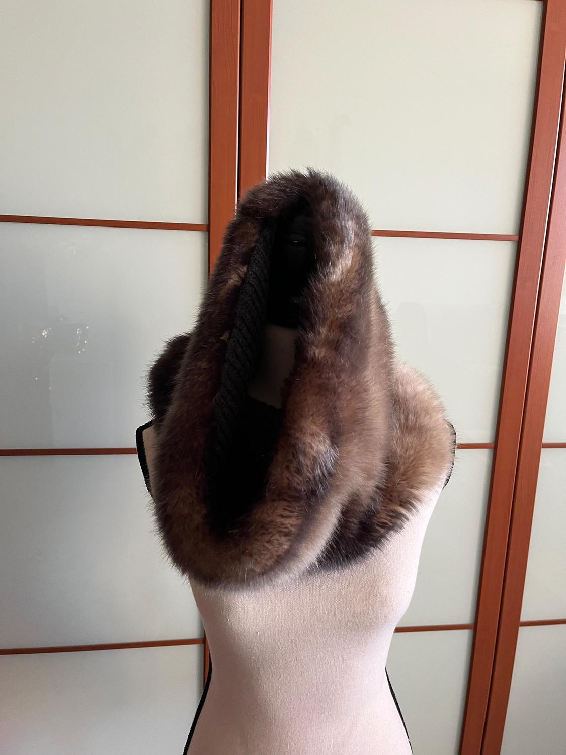 Mannequin with brown fur scarf against a background of white sliding doors with wooden frames.