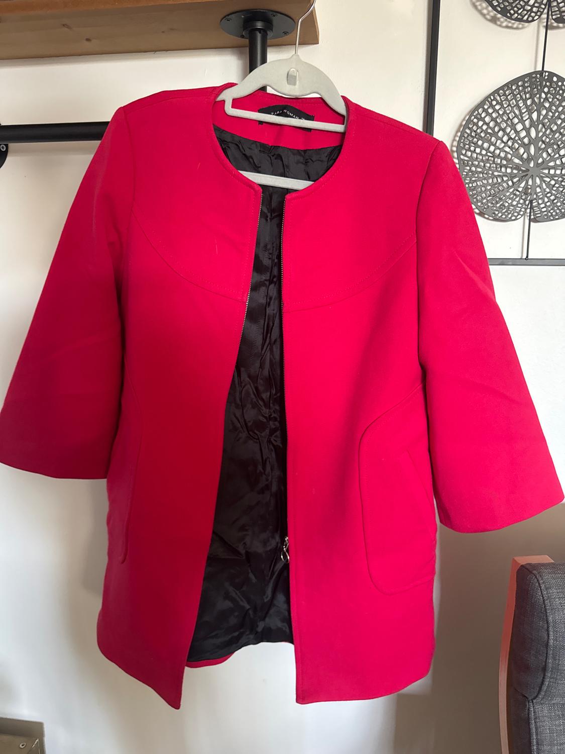 Front view of a red jacket with side pockets and a black lining.