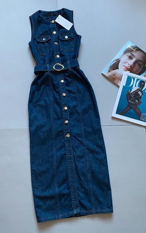 Long blue denim dress with gold buttons and a belt, next to two fashion magazines on the floor.