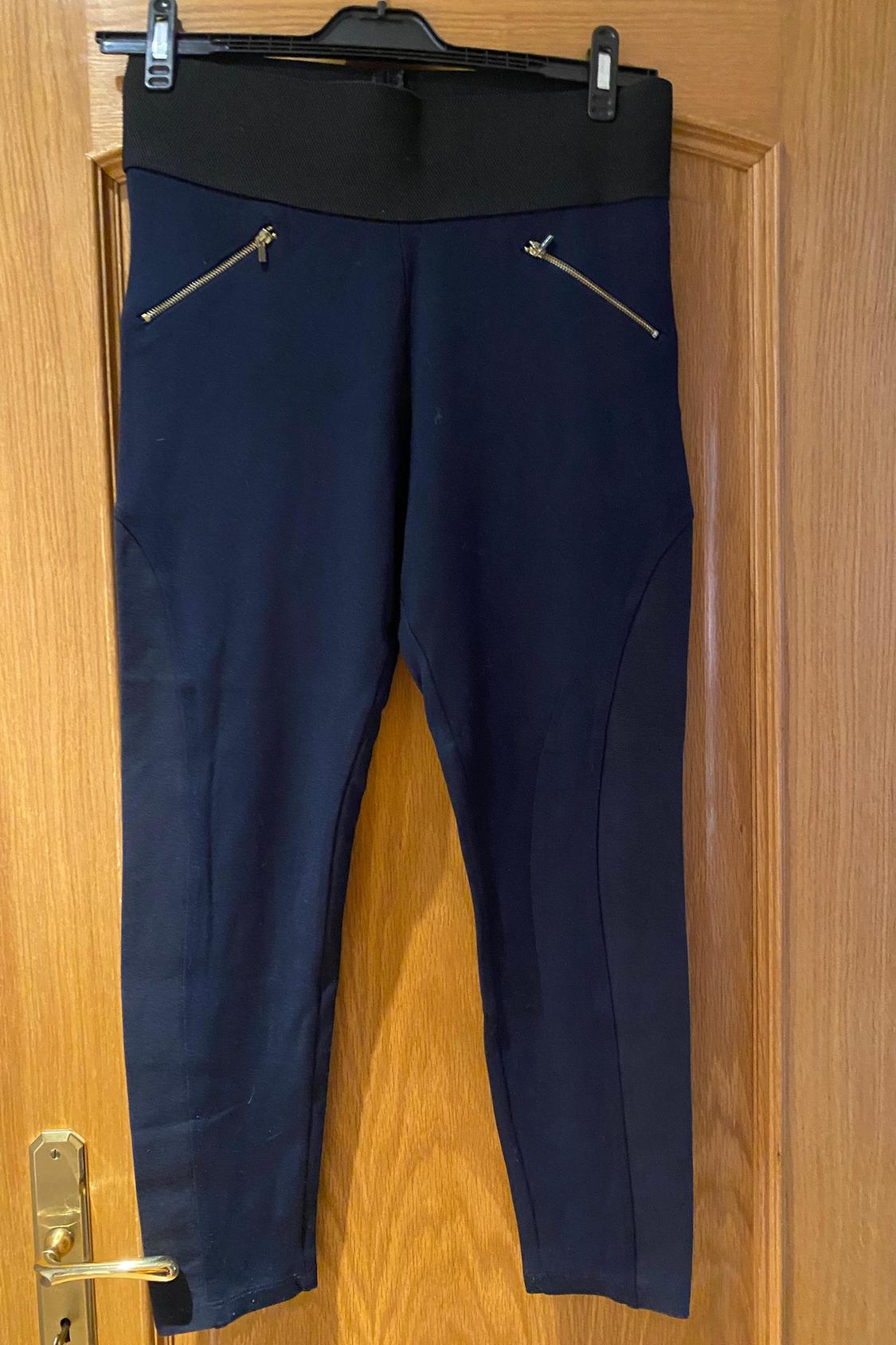 Front view of black trousers with zips on side pockets.