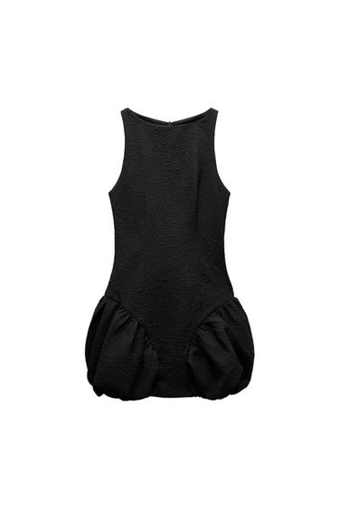Front view of textured black dress with ruffle detail at the bottom.
