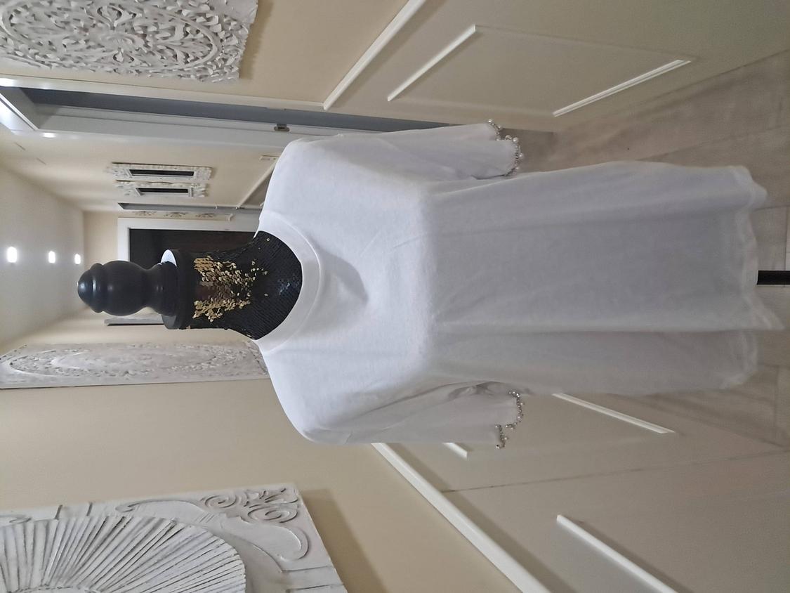 Mannequin in a short-sleeved white T-shirt in a hallway decorated with white ornamental wall panels.