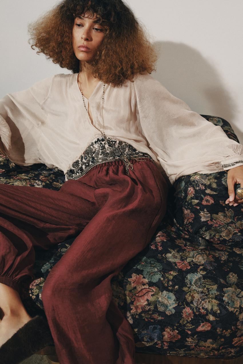 Light pink blouse set with round neck, V-neck and embroidery on the waistband, and burgundy wide-leg pants.