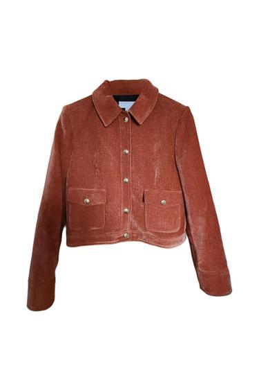 Brick-coloured cropped velvet jacket with a classic collar, metallic front buttons and two flap pockets on a white background.