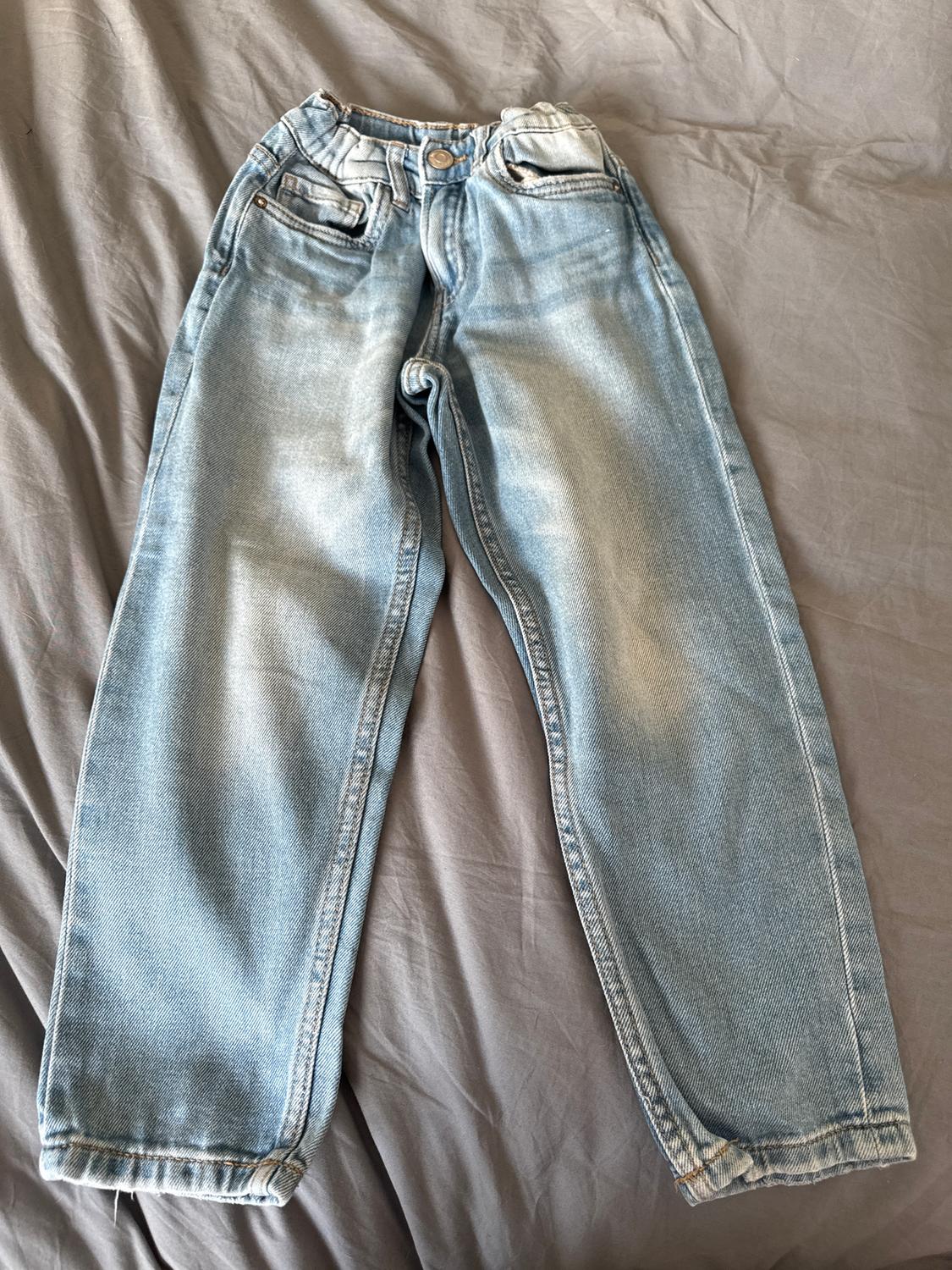 Light blue distressed jeans, placed on a grey surface.