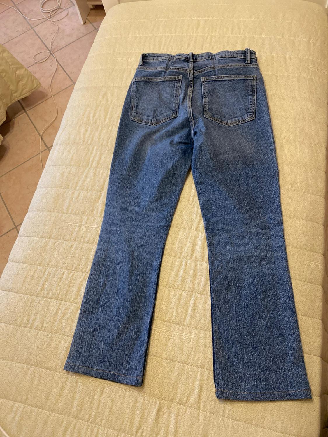 Μπλε τζιν παντελόνι ιδωμένο από πίσω, απλωμένο πάνω σε ένα ανοιχτόχρωμο
κρεβάτι σε ένα χαλαρό οικιακό περιβάλλον.