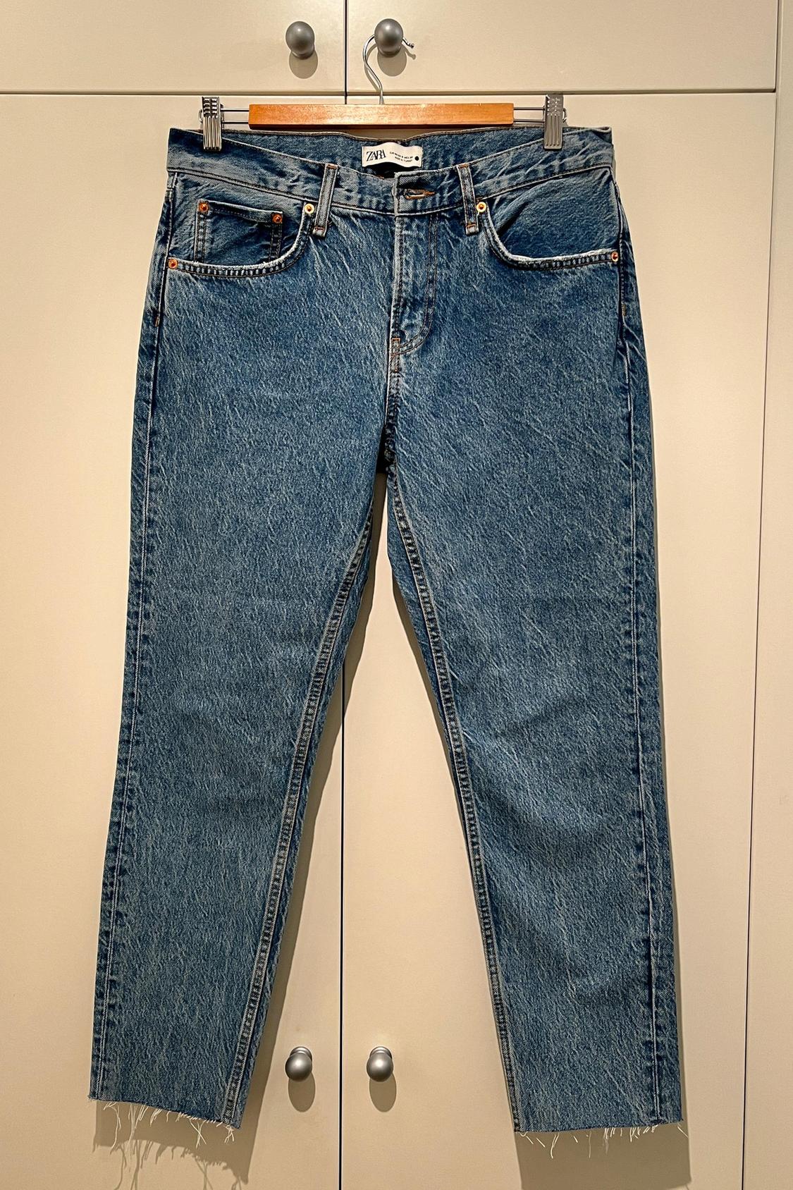Front view of blue jeans with front pockets and frayed hem.