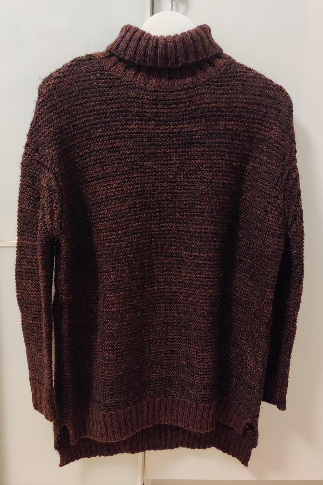 Rear view of a dark brown chunky knit jumper with a roll neck and long sleeves.
