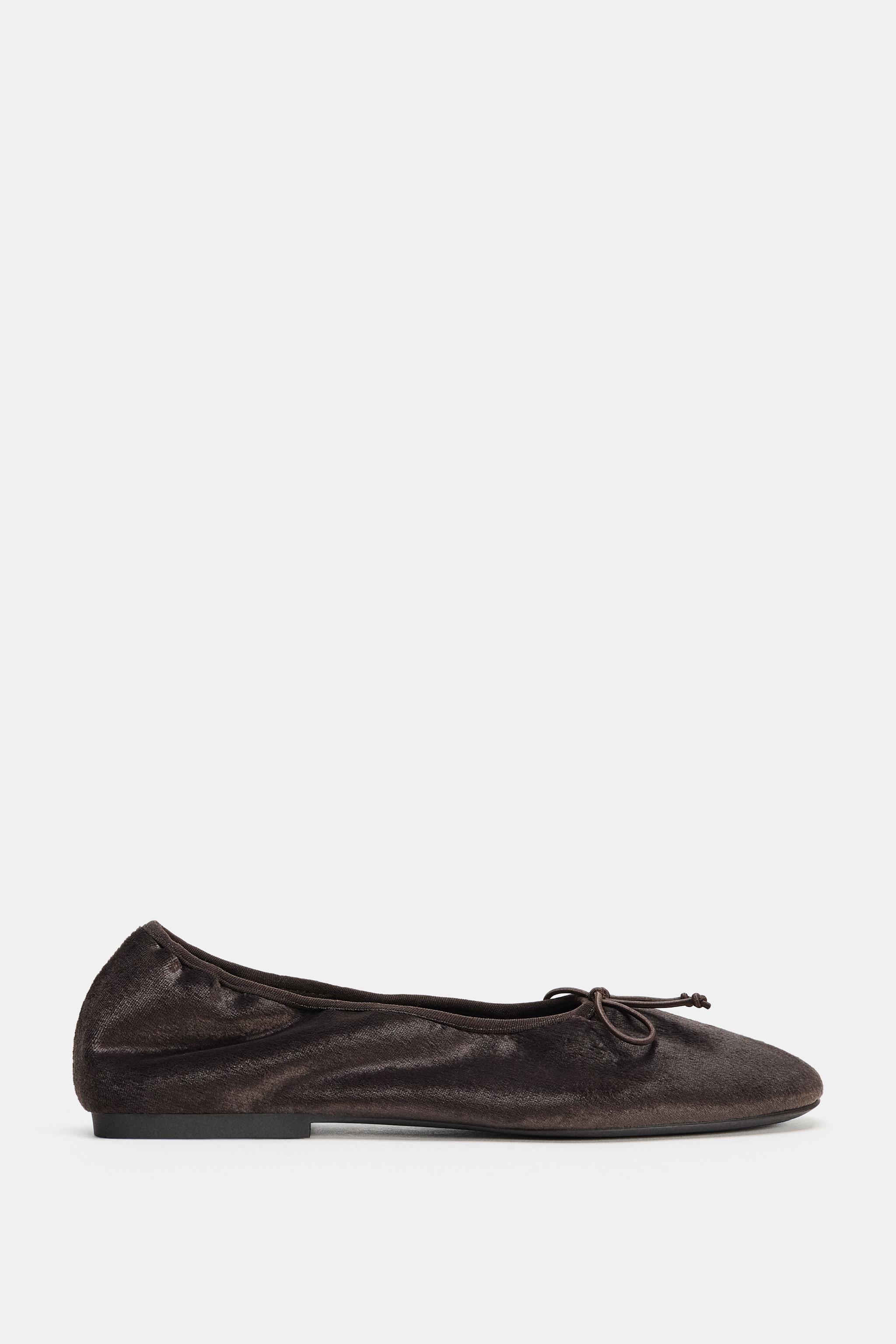 Side view of dark brown flat with decorative bow on top and black flat sole.
