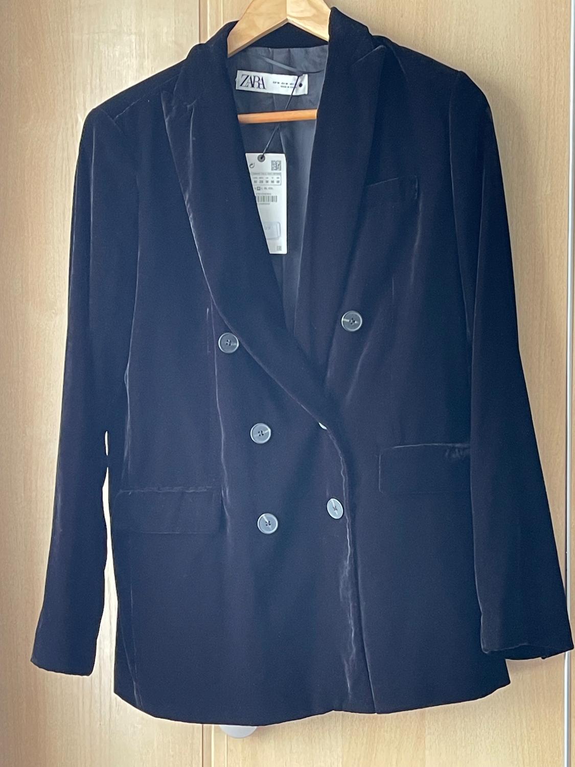 Black double-breasted velvet jacket hanging on a wooden hanger. Visible label with the Zara logo.