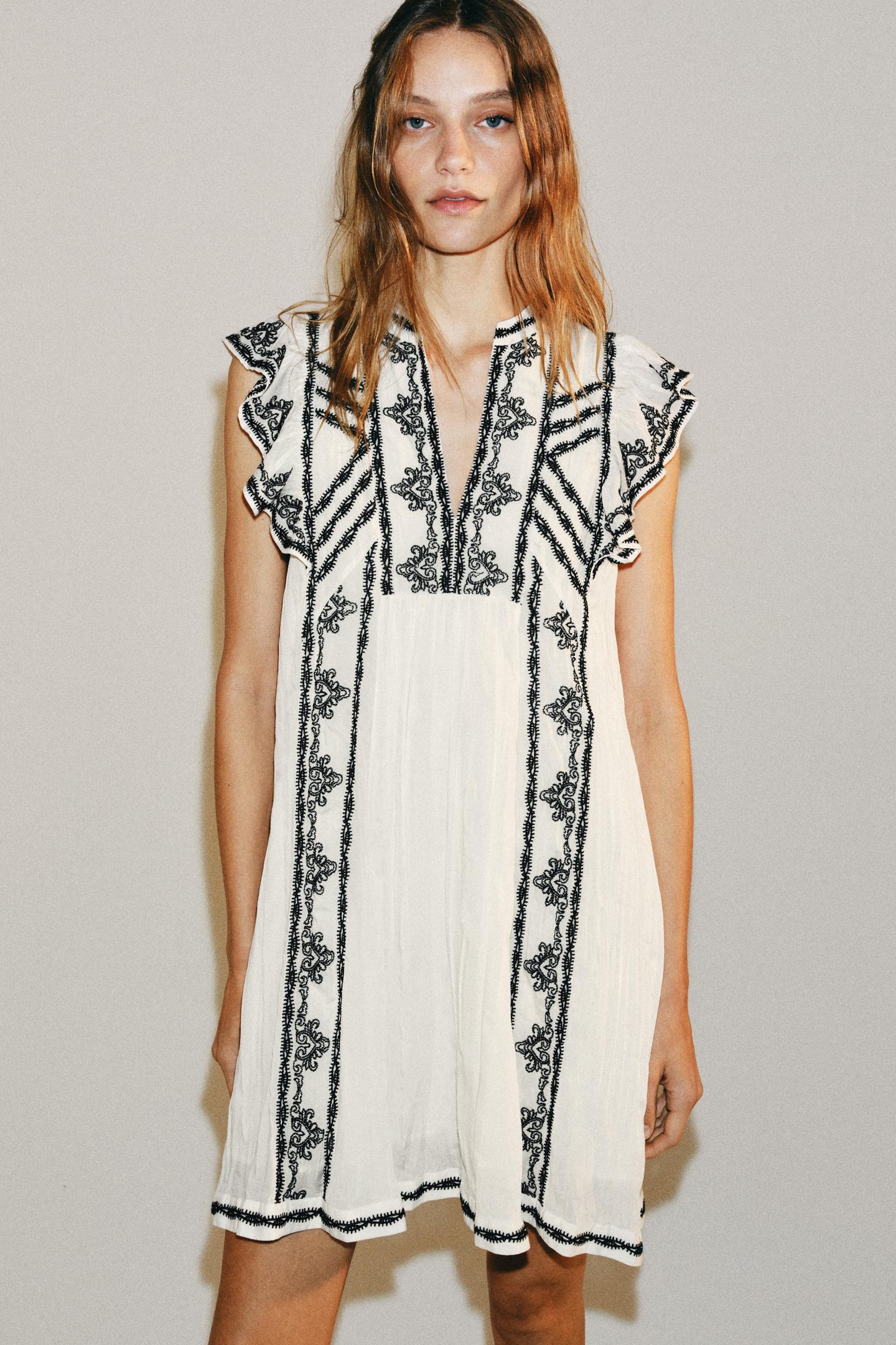 Vestido corto blanco con bordados negros.