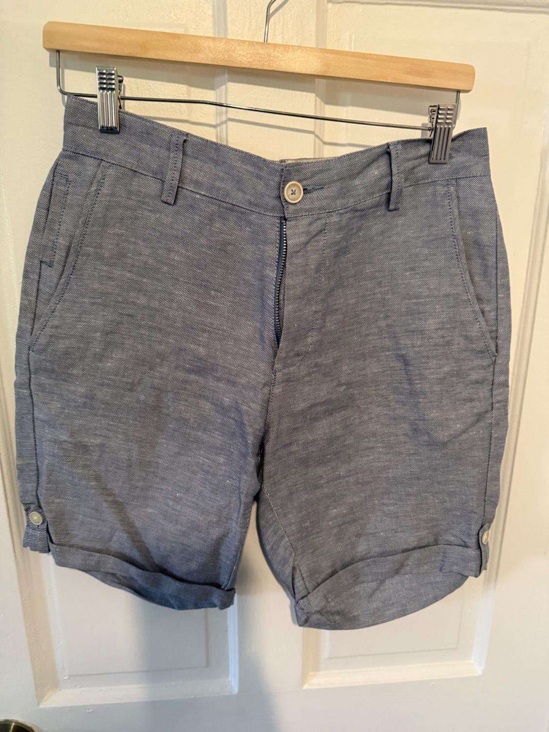 Front view of grey shorts with side pockets and a front button.