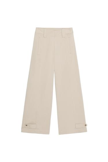 Front view of beige wide-leg trousers with side pockets and belt loops on the hem.
