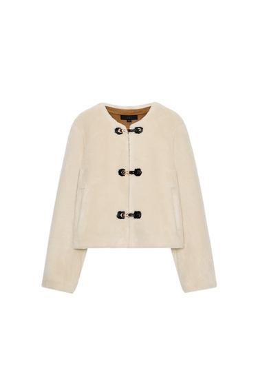 Front view of a beige bomber jacket with a round neck, long sleeves, and toggle fastening. Front jetted pockets.