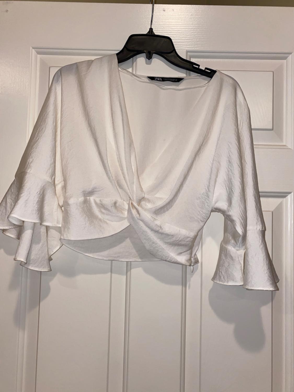 Front view of a white blouse with puffed sleeves and a crossover neckline.