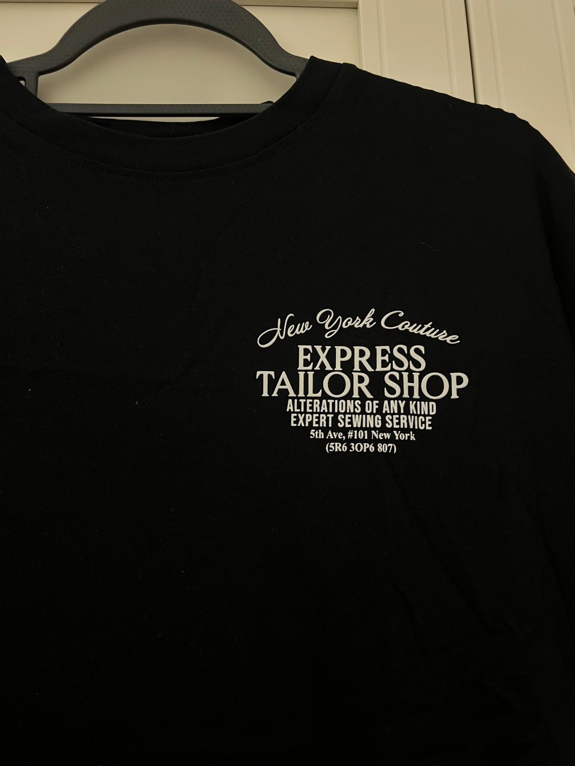Black T-shirt with white text: "New York Couture EXPRESS TAILOR SHOP ALTERATIONS OF ANY KIND EXPERT SEWING SERVICE 5th Ave, #101 New York (5R6 30P6 807)".