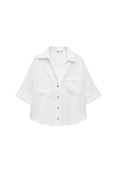 Front view of a white shirt with front pockets and brown buttons.