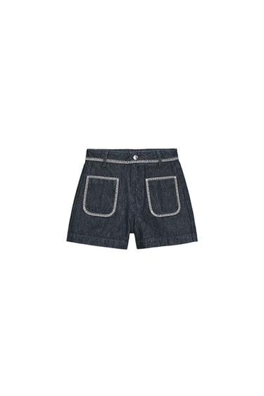 Front view of high-waisted blue shorts with patch pockets on the front and contrasting embroidered topstitching. Zip and button fastening.