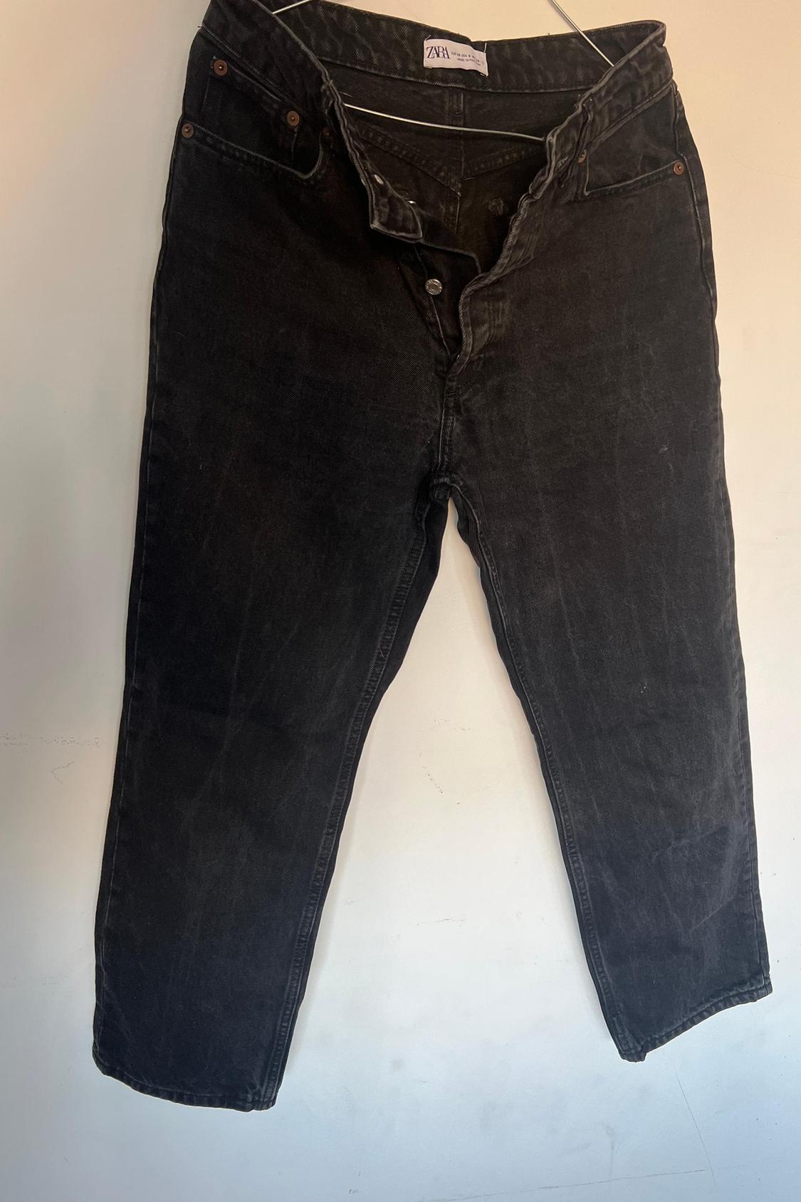 Front view of black trousers with button fastening and side pockets.