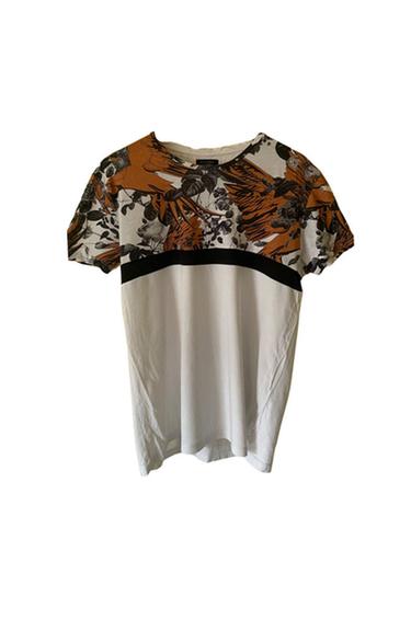 Front view of a t-shirt with an orange and black floral print on the upper part.
