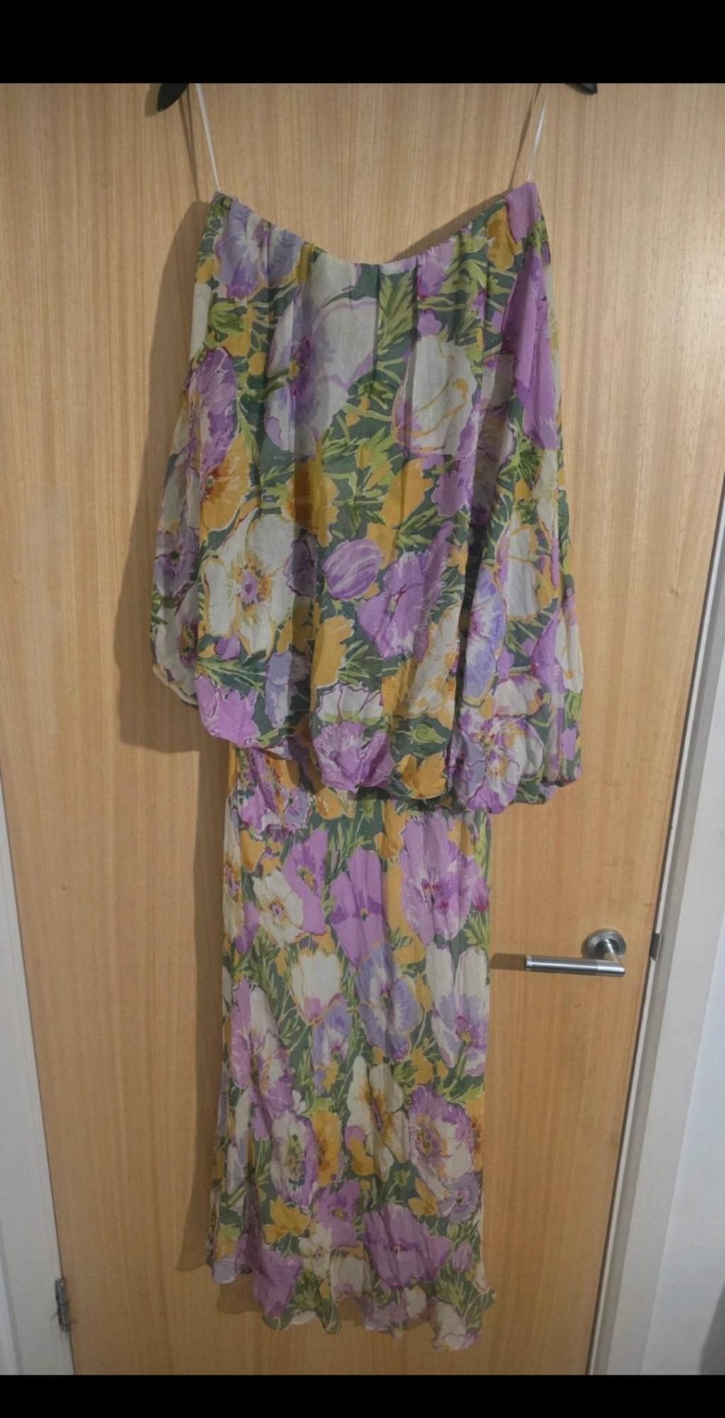 Floral dress with thin straps, purple, yellow, and green floral print, hanging on a light wooden door.