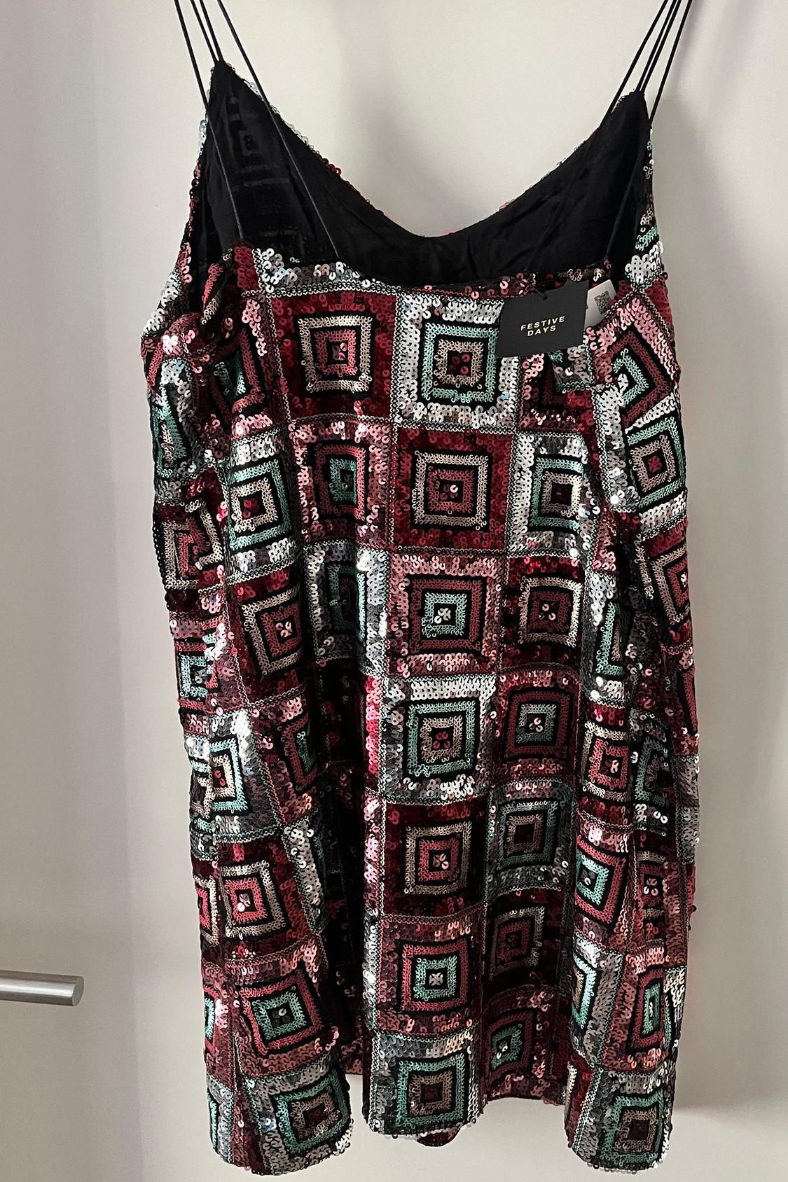 Front view of dress with thin straps and geometric sequin print in red, black and green.