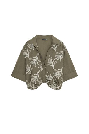 Front view of a khaki short-sleeved shirt with white embroidery, shirt collar, short turn-up sleeves, and front button fastening.