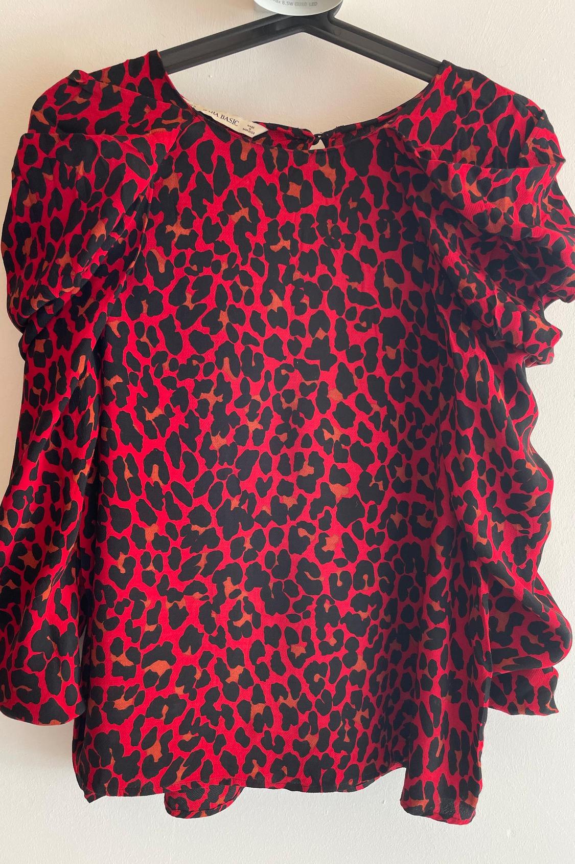 Front view of red blouse with black leopard print and puff sleeves.