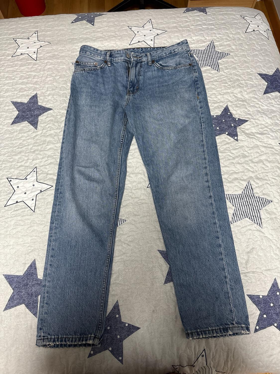 Casual blue jeans, laid out on a bed with a white bedspread decorated with blue stars.
