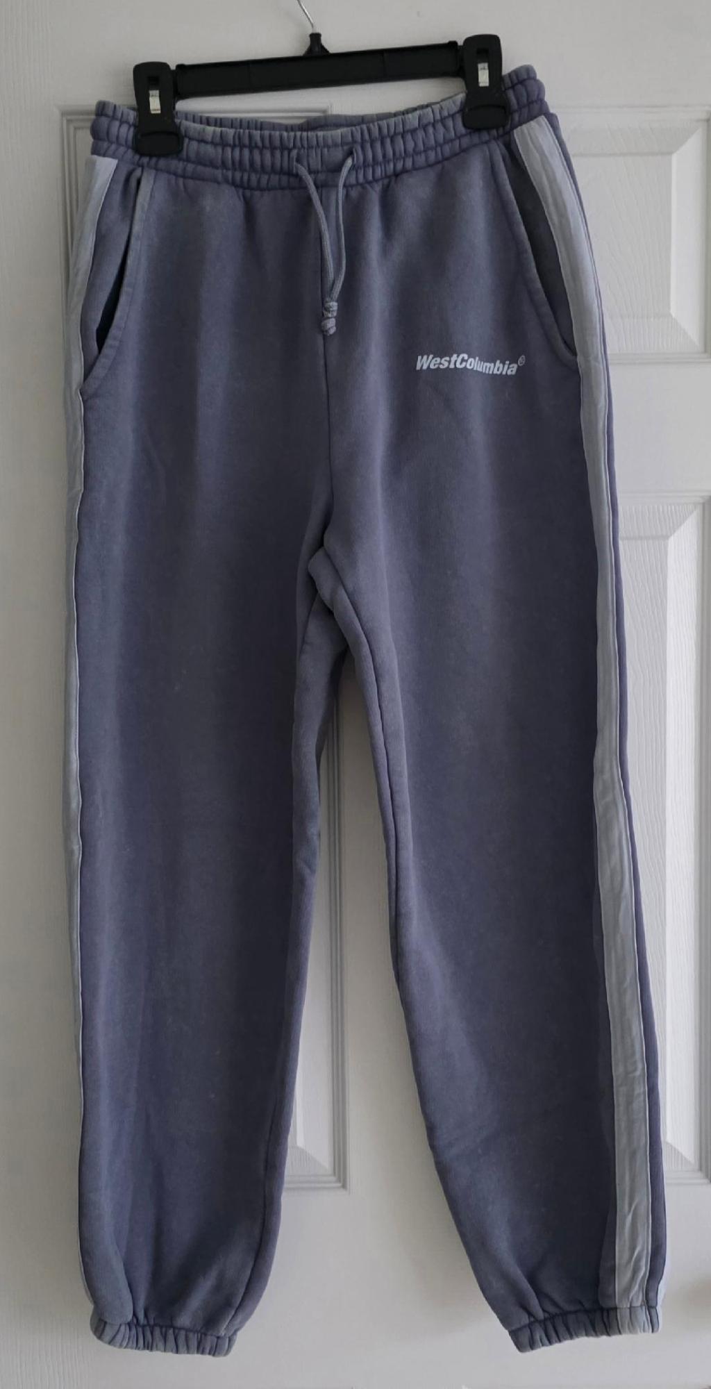Gray sweatpants hanging on a black hanger, with the text "WestColumbia" on the left side. White door in the background.