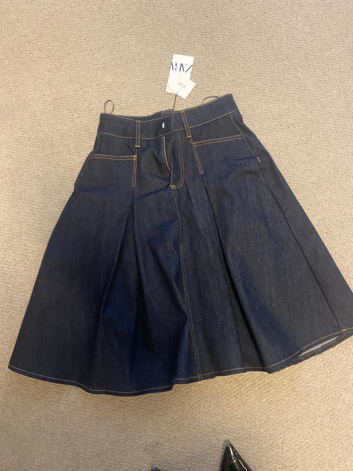 Front view of denim skirt with side pockets and visible stitching.