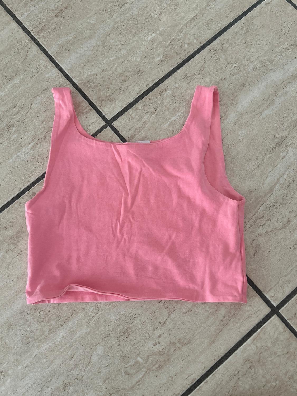 Pink sleeveless crop top on a light tiled floor with black lines.