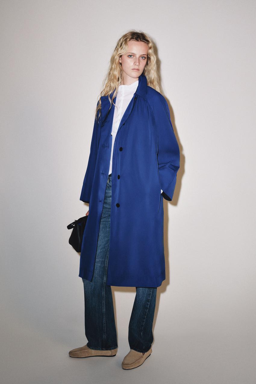 Long blue coat outfit with dark collar and buttons, white shirt, blue jeans, and beige loafers.