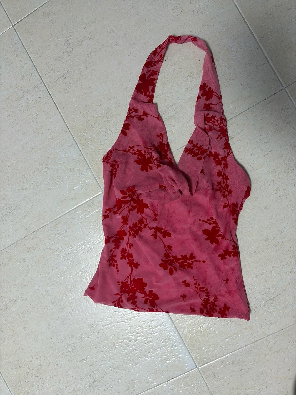 Ροζ crop top με halter λαιμόκοψη και κόκκινο φλοράλ σχέδιο, τοποθετημένο σε ανοιχτόχρωμο πλακόστρωτο πάτωμα.
