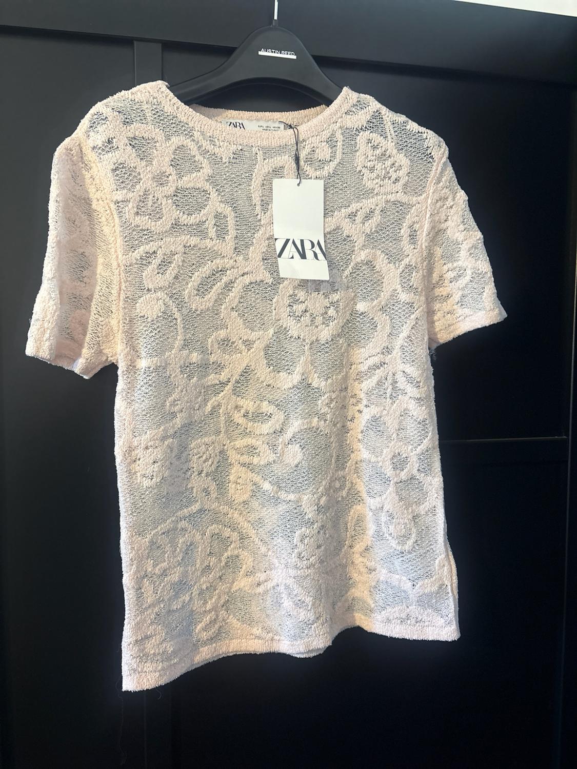 Pale pink floral textured short-sleeve sheer T-shirt on a black hanger. Text: AUSTIN REED, ZARA.