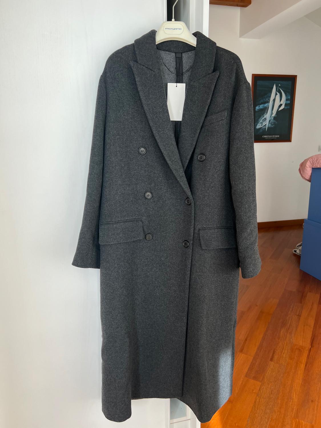 Dark grey wool coat hanging on a Morgano hanger, in a room with a wooden floor and a sailboat painting on the wall.