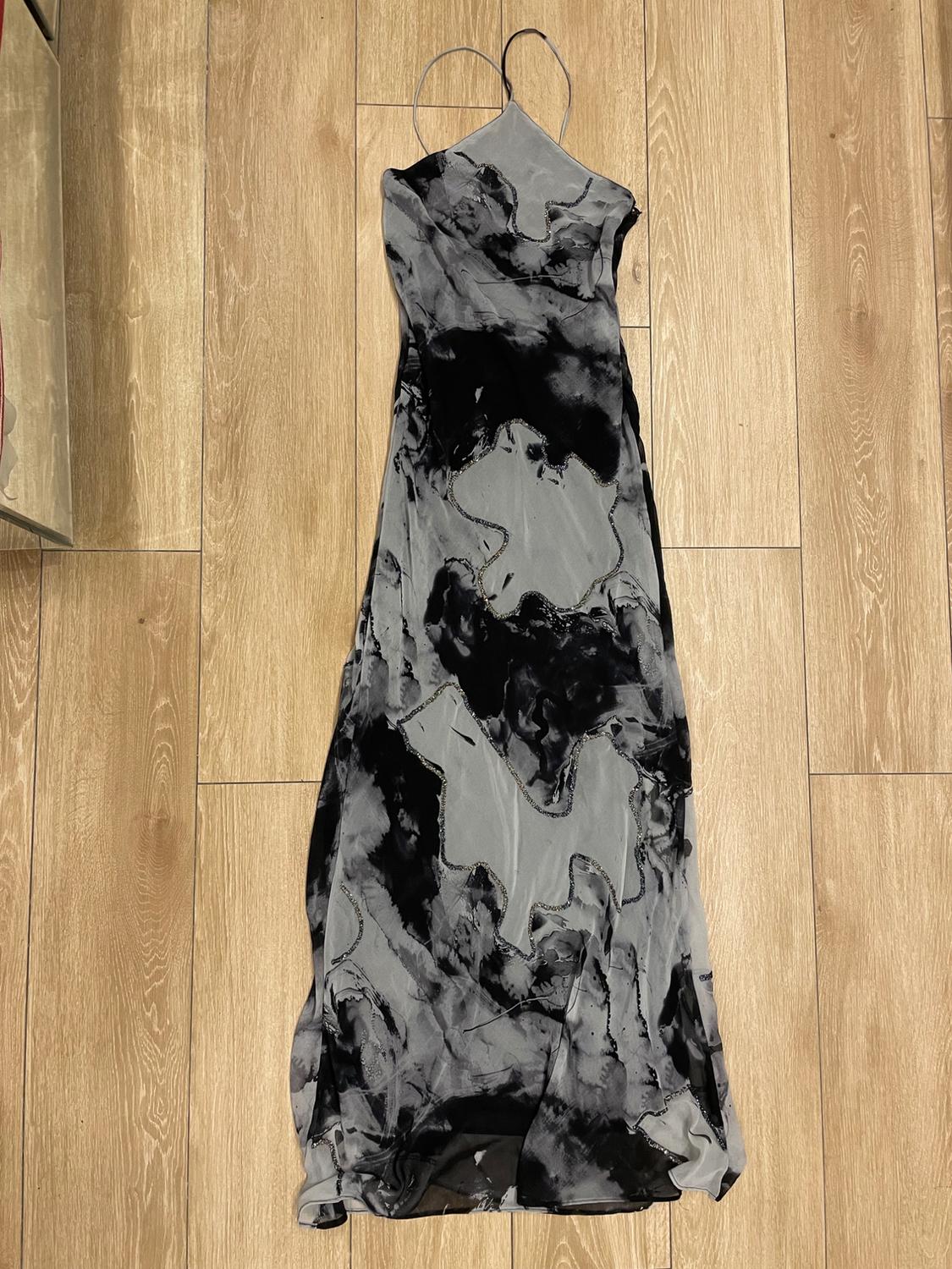 Long dress with thin straps and abstract black and white print, on a light wooden floor.