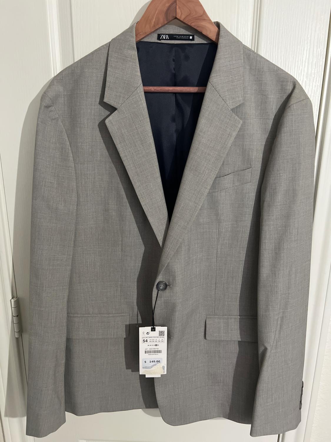 Gray jacket hanging on a wooden hanger, with a visible tag showing the price of $149.00. White door background.