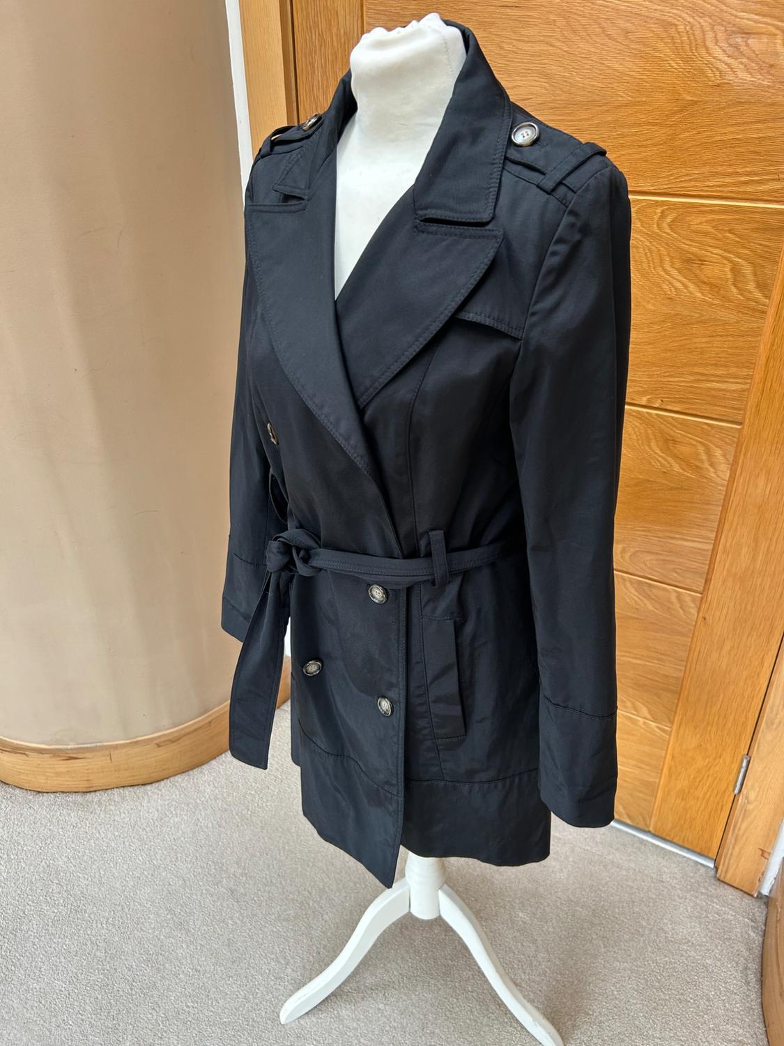 Side view of a black coat with double buttons and a belt tied at the waist.