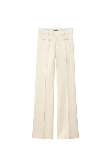 Cream dress trousers with front pleats and side pockets, presented on a white background.